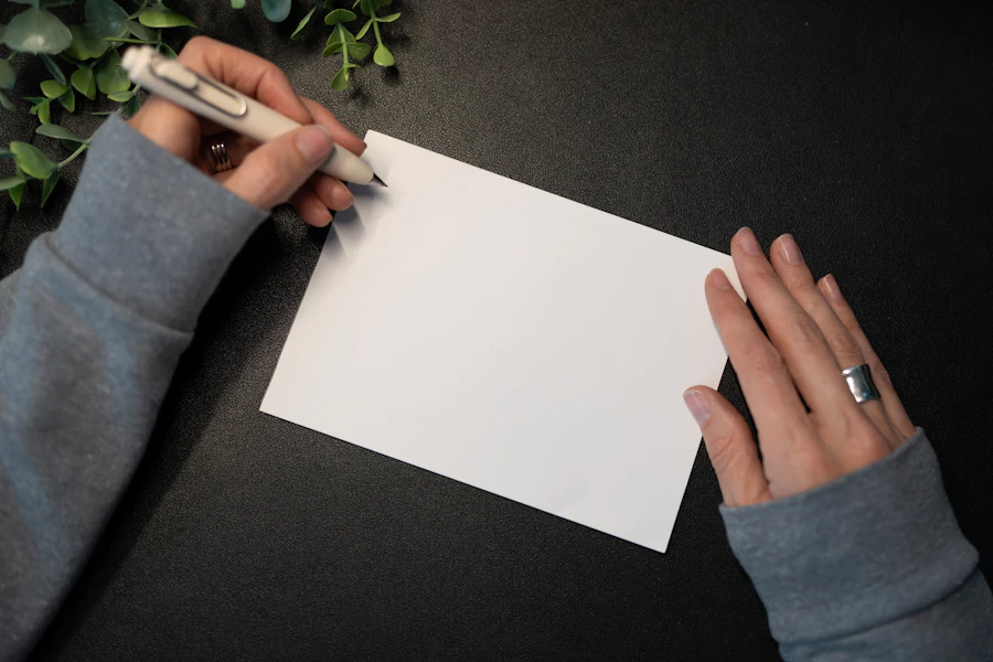 Hands writing a message inside a blank greeting card